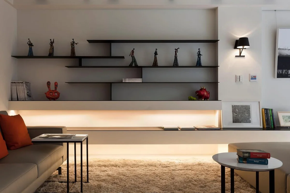 A sophisticated modern living room featuring a curated console display with a sculptural ceramic vase, abstract figure, decorative bowl, and subtle metallic accents.