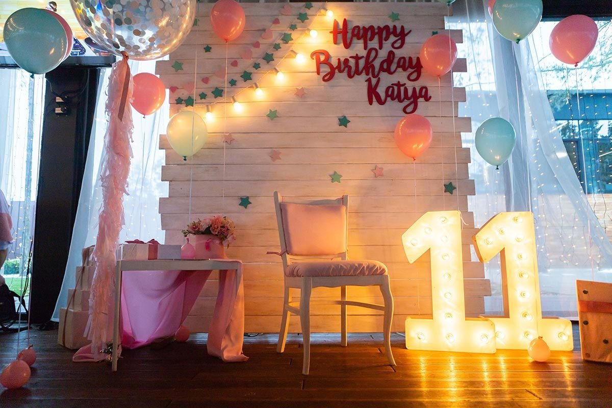 beautifully decorated room for a birthday celebration with lights balloons and a birthday backdrop