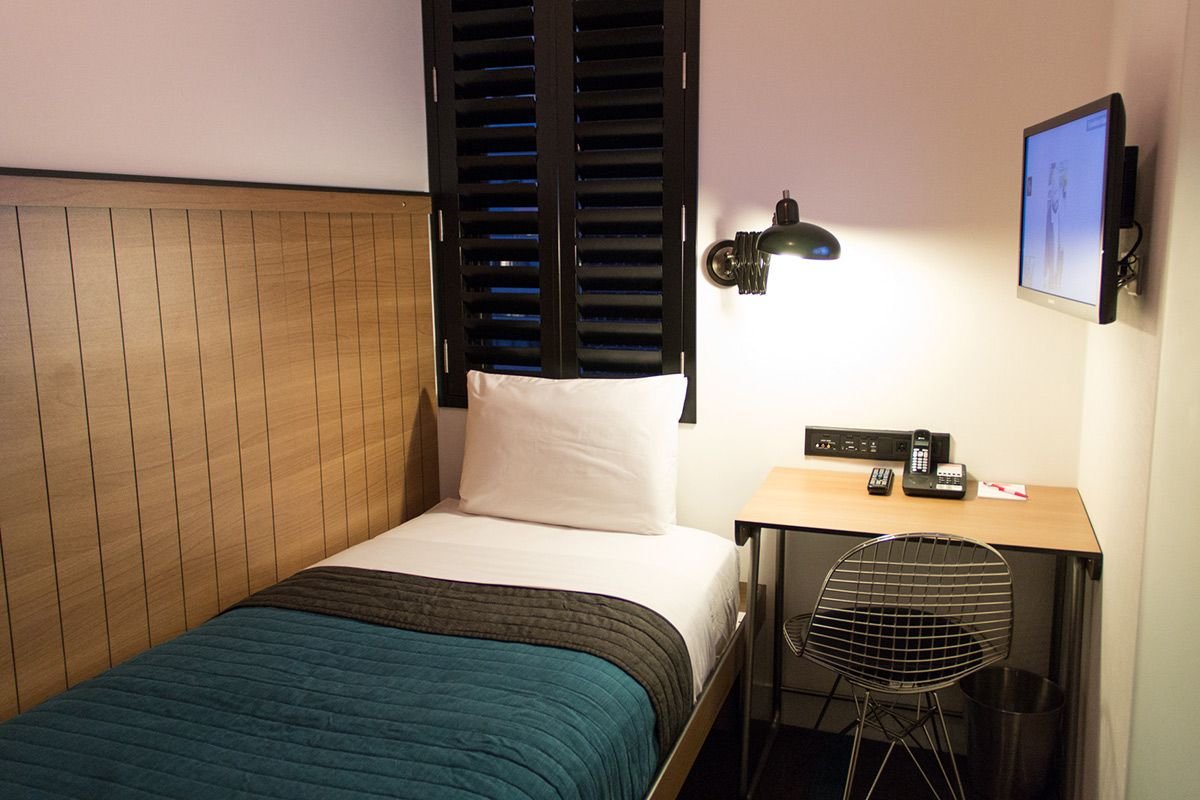 small hotel room with stylish feature wall behind the bed